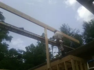 Carpenter setting a ridge beam over a new addition frame — Ice Dam Removal by Roofing Brothers in Barre