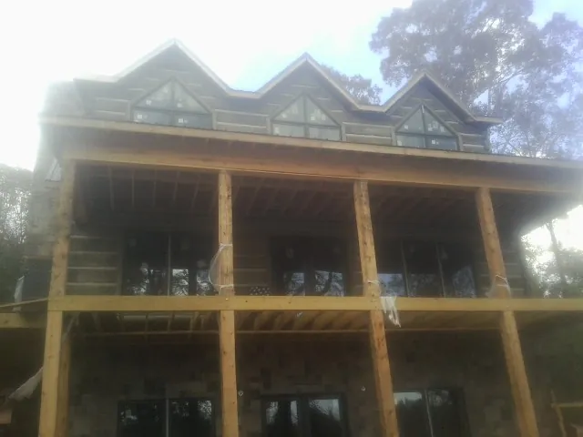 Dormers and porch framing on a large log home under construction — Roof Coating work by our crew in Barre
