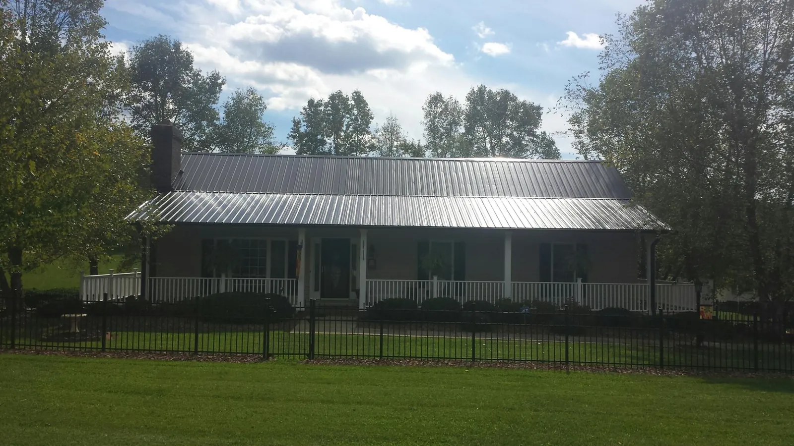 Gray metal roof on a brick ranch with a full width front porch — Gutter Guard Installation work by our crew in Barre