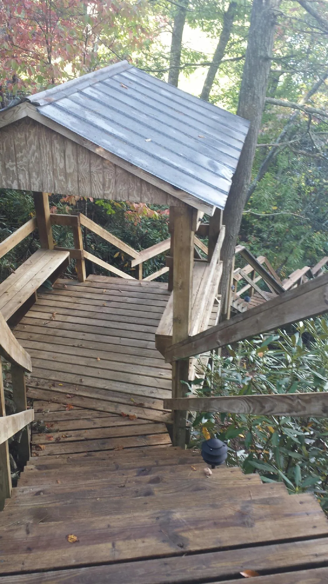Metal roofed shelter over wooden steps on a wooded walkway — Skylight Repair & Installation work by our crew in Barre